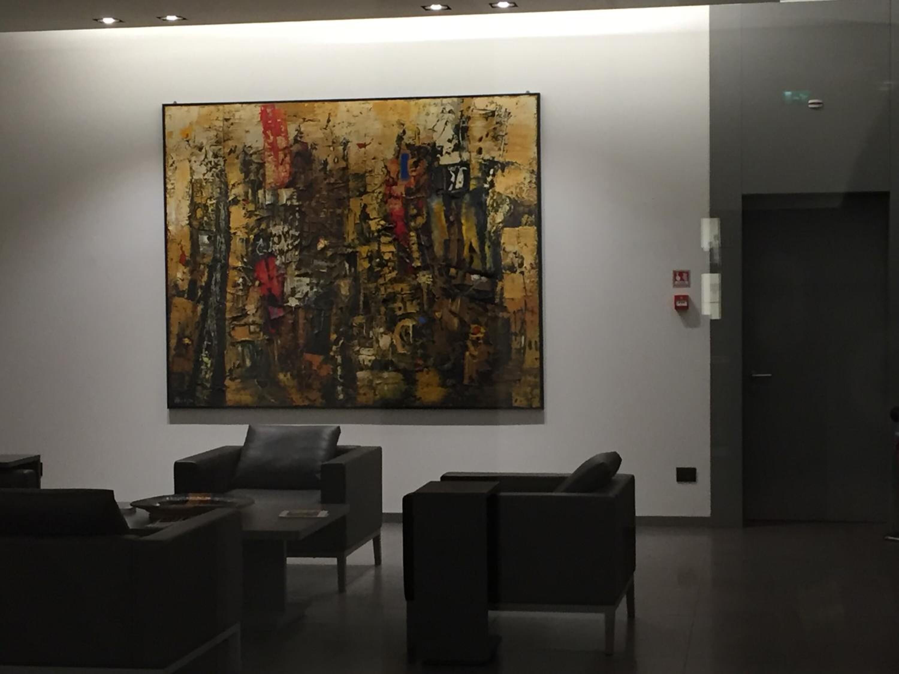 Um hall de entrada com uma grande pintura abstrata na parede, um balcão de recepção e dois sofás.
