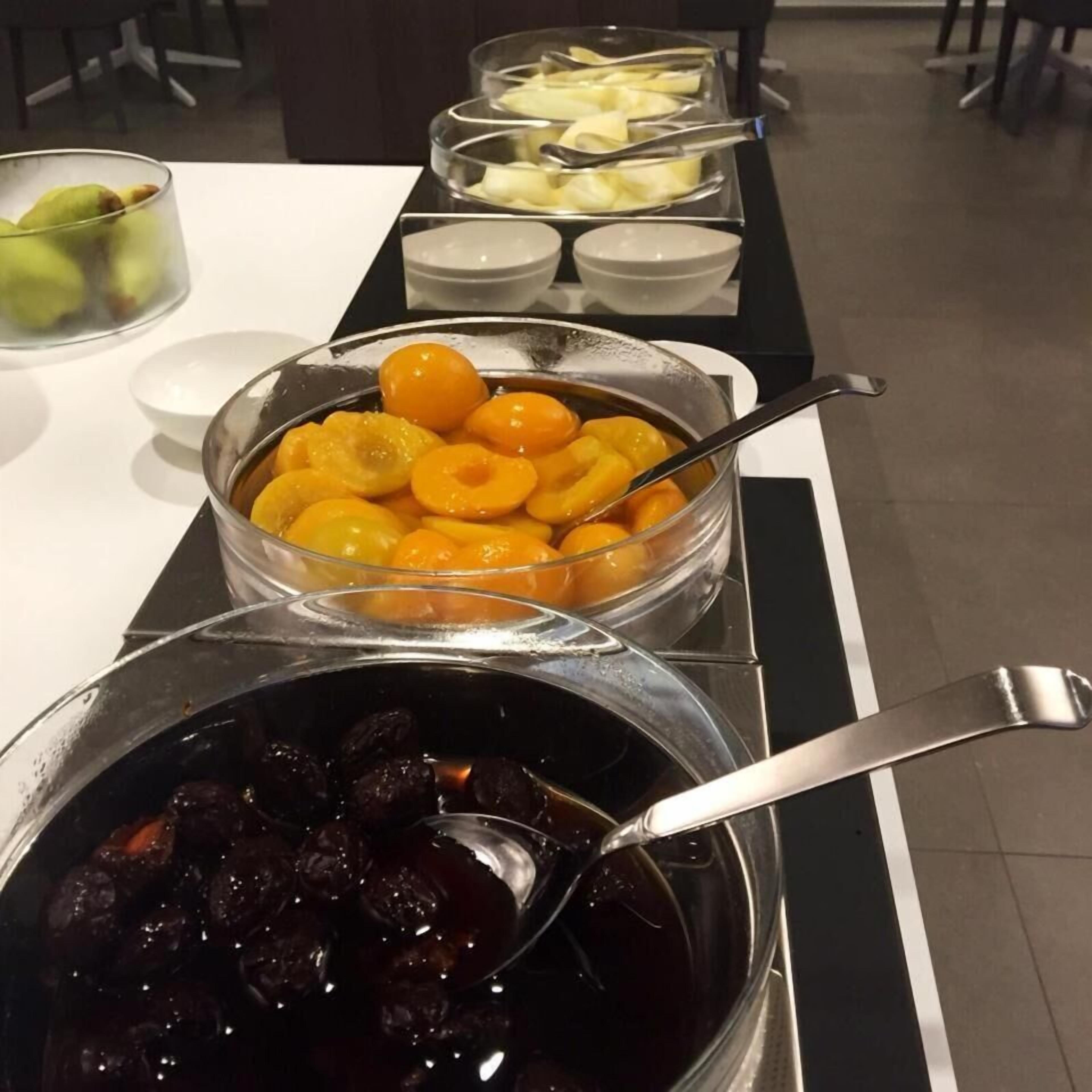 A buffet with various food items including fruits and a dark-colored dish, possibly a dessert.