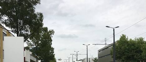 A street with a tram, buildings, and greenery.