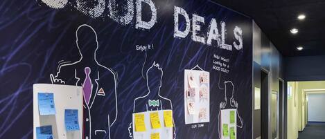 A wall with silhouettes of people and text reading "GOOD DEALS".