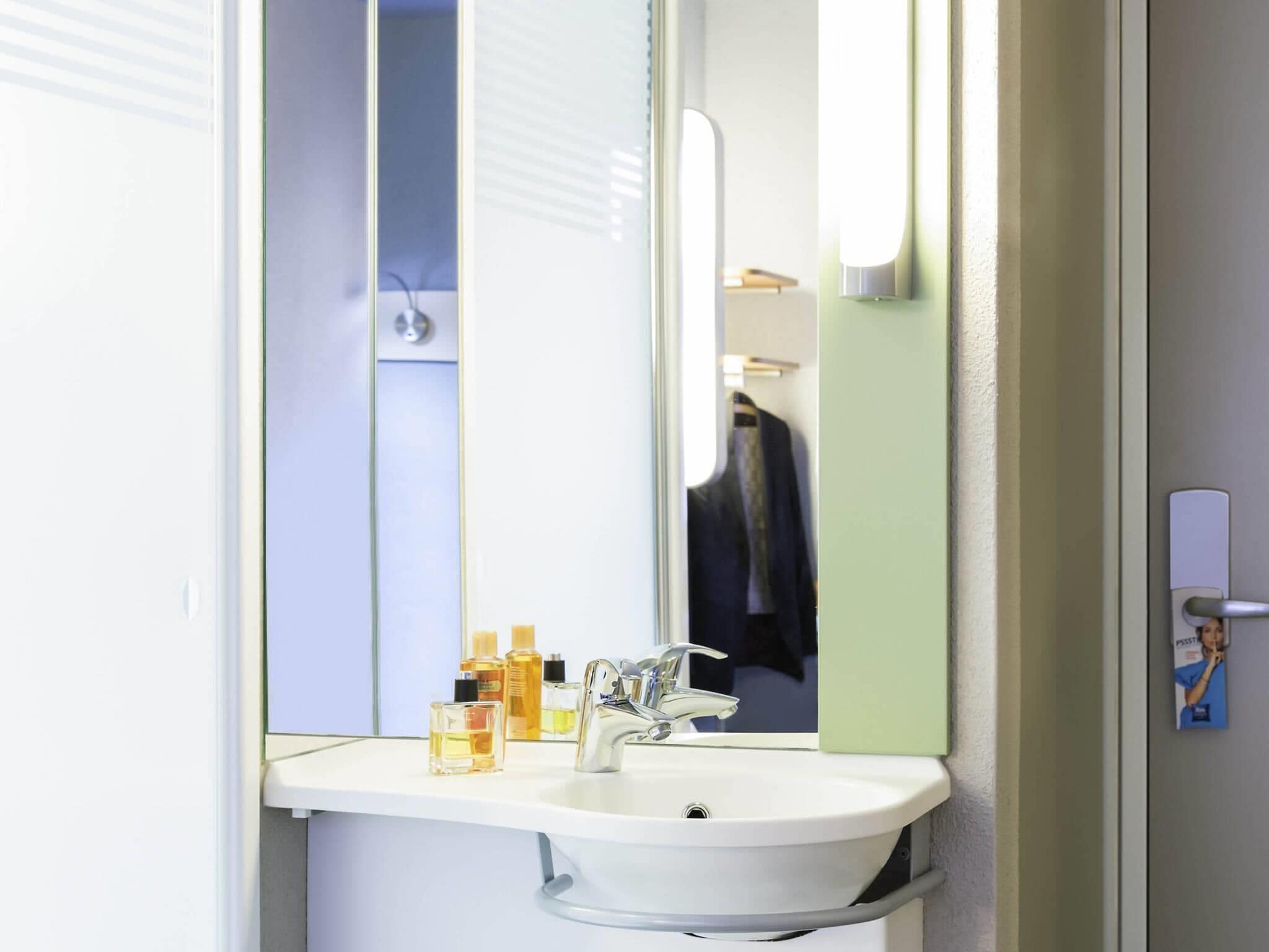 A bathroom with a white sink, a mirror, and a towel rack.