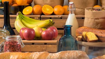A wooden table with fruits, bread, and a bottle.