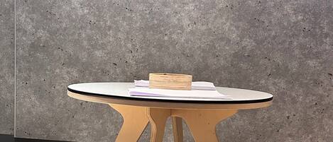 A small wooden table with a white top and three matching stools.