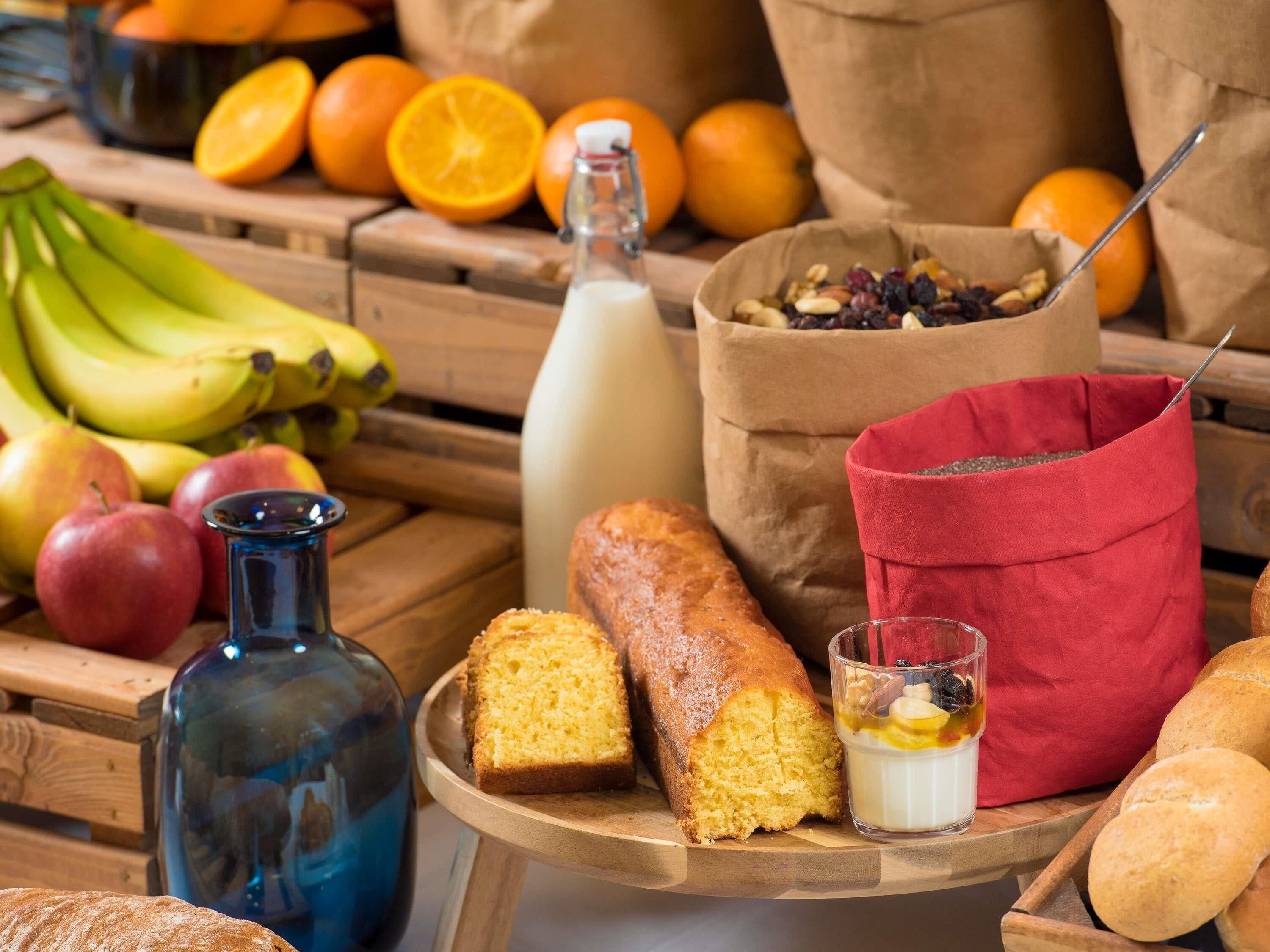 A wooden table with bread, a bottle, and a bowl of fruit.