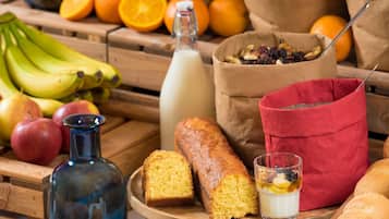 Una mesa de madera con pan, una botella y un cuenco de fruta.
