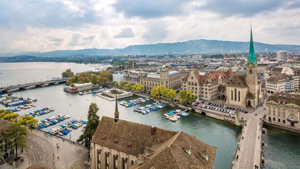 Eine Stadtansicht mit einem markanten Kirchturm, einem Fluss und einer Brücke.