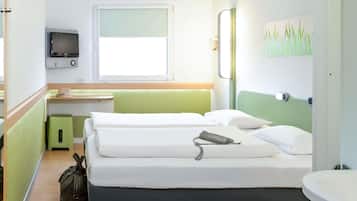 Una habitación de hotel con cama, escritorio, televisor y un cuadro en la pared.