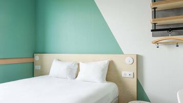 A neatly arranged hotel room with a bed, bedside table, and a small round table.