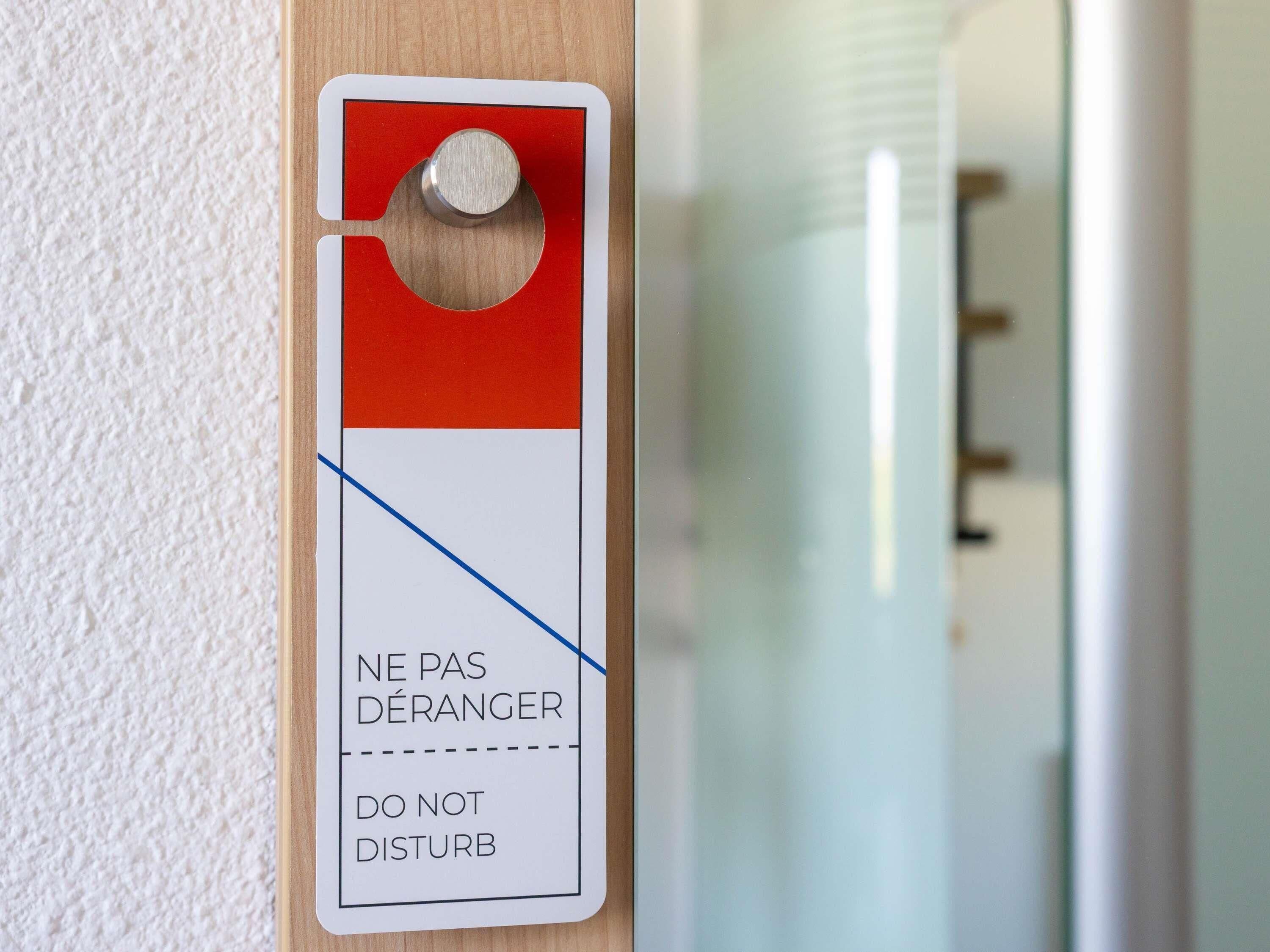 Una puerta con un cartel rojo y blanco que dice 'NE PAS DÉRANGER DO NOT DISTURB' en francés.