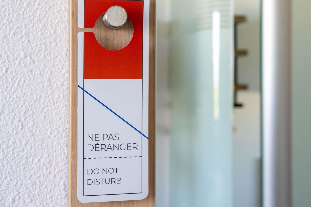 Une porte ornée d’une pancarte rouge et blanche sur laquelle on peut lire : « NE PAS DÉRANGER ».