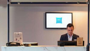 Una mesa de recepción con encimera de mármol, una computadora y un monitor que muestra 'ibis budget'.