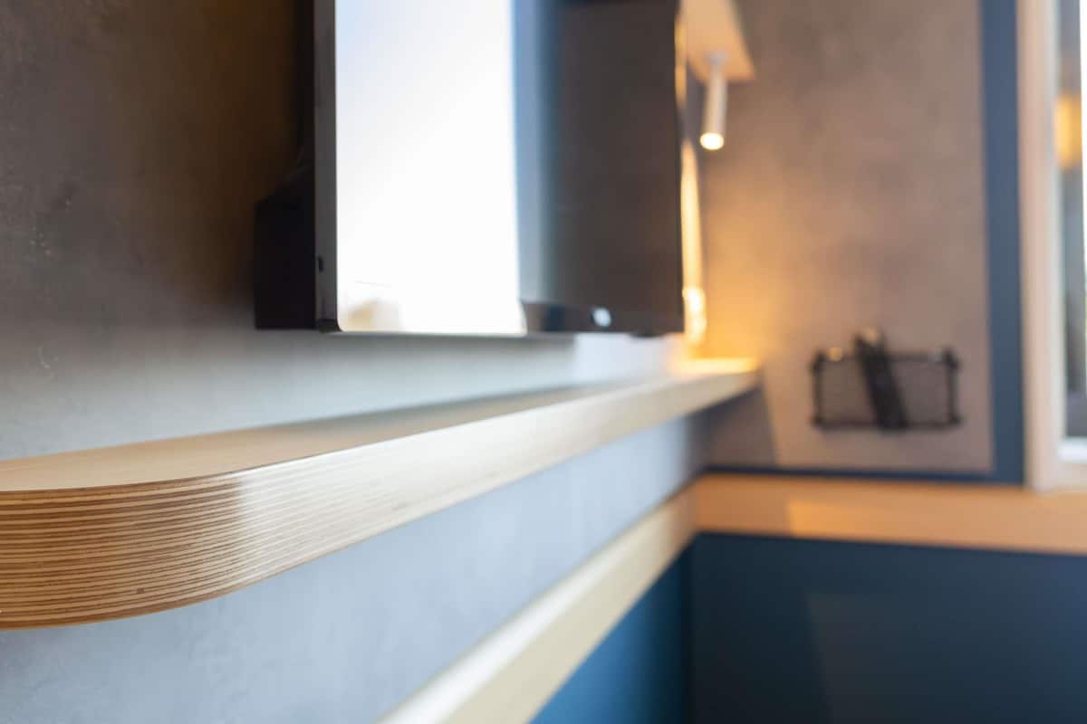 A modern interior with a wooden counter, a wall-mounted television, and a dark-colored door.