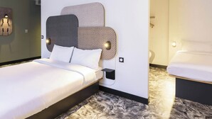 A modern hotel room with a large bed, a bedside table, and a small bedside lamp.