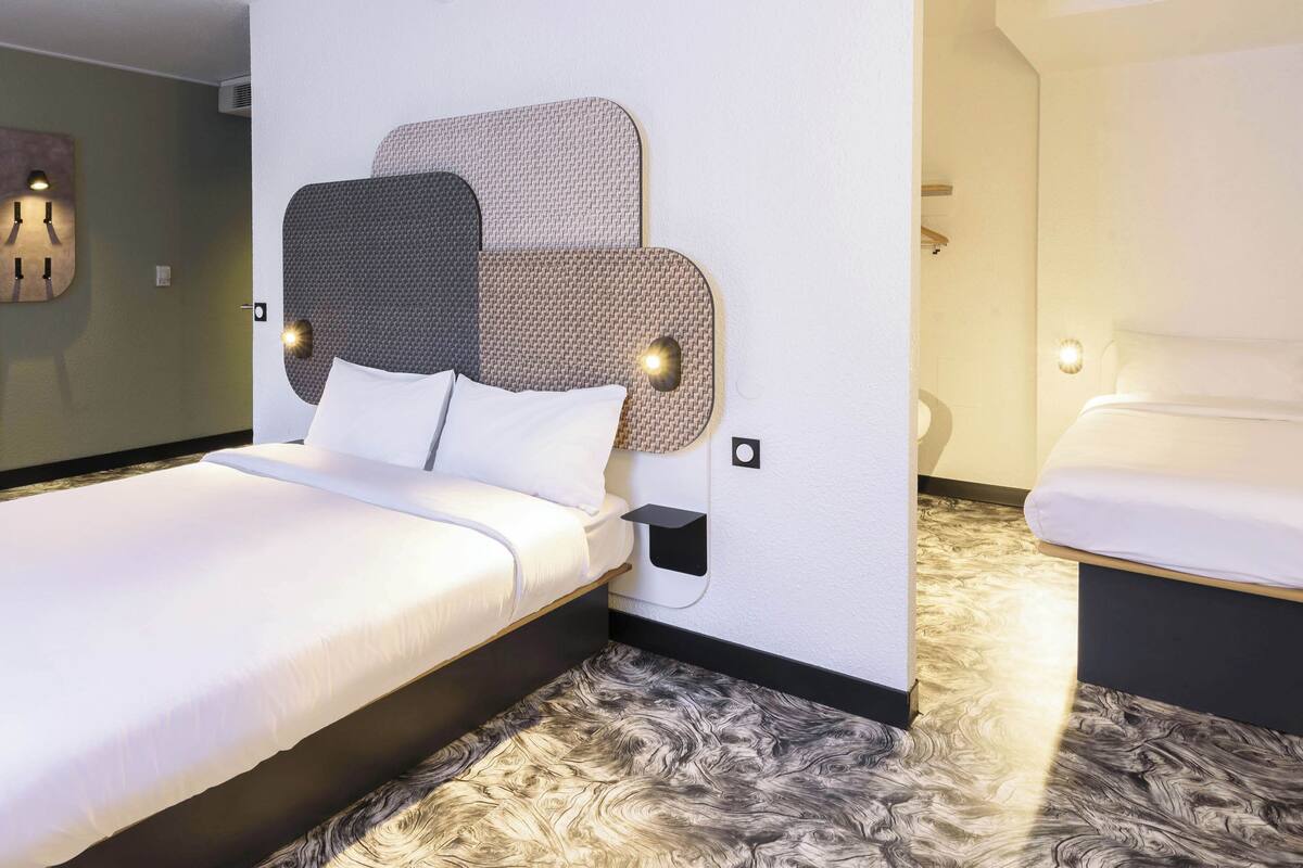 A modern hotel room with a large bed, a bedside table, and a small bedside lamp.