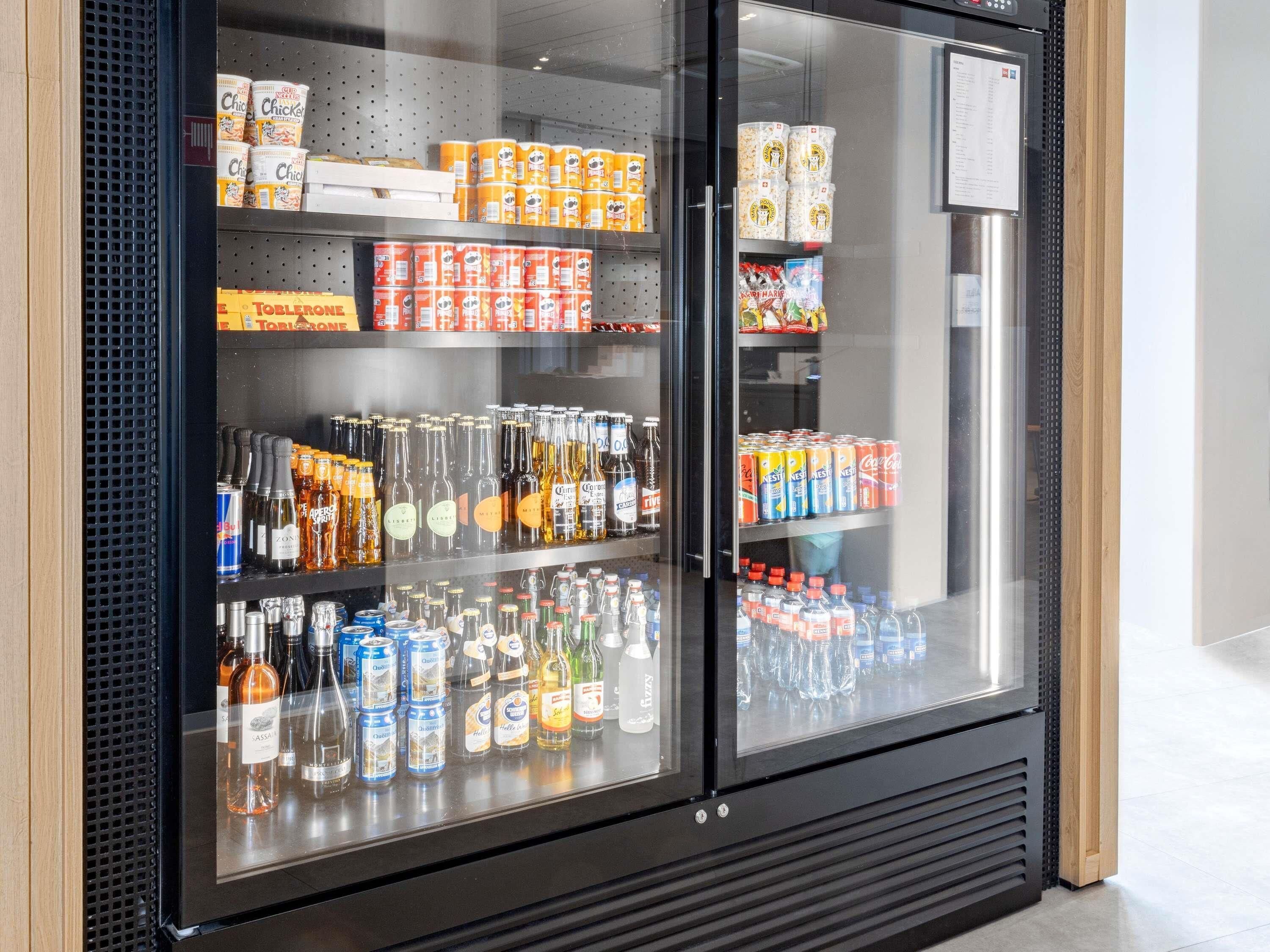 Un refrigerador para bebidas repleto de varias opciones, incluyendo cerveza, vino y refrescos.