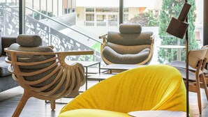 Ein modernes Interieur mit einem gelben Sofa, einem Holzstuhl mit einem außergewöhnlichen Design und einer Metalllampe.