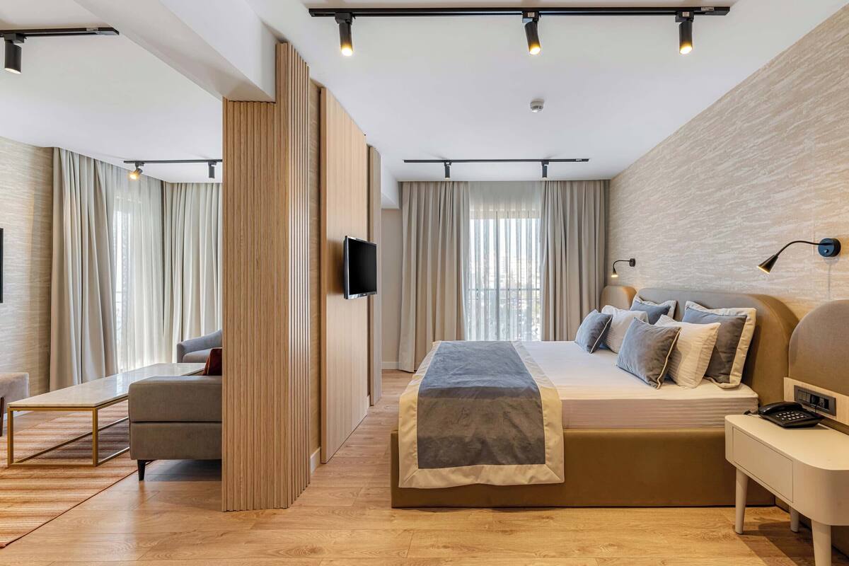 Une chambre d’hôtel moderne avec un grand lit, une table de chevet et un téléviseur à écran plat.