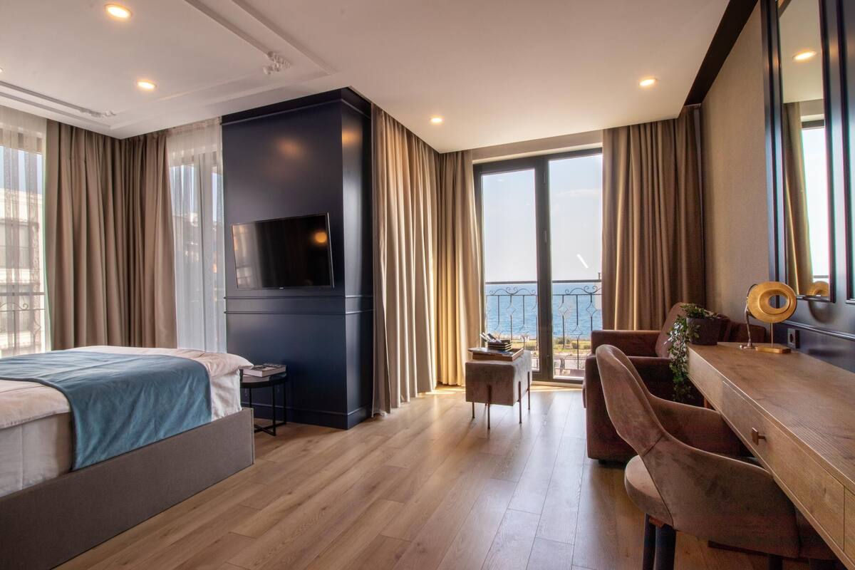 Une chambre d’hôtel moderne dotée d’un grand lit, d’un bureau, d’une télévision et d’un balcon avec vue.