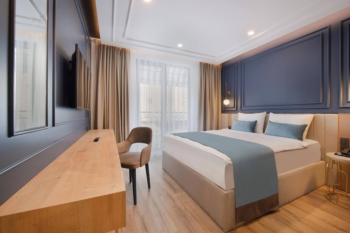 Une chambre d’hôtel avec un lit, un bureau, une chaise et une vue sur l’extérieur.