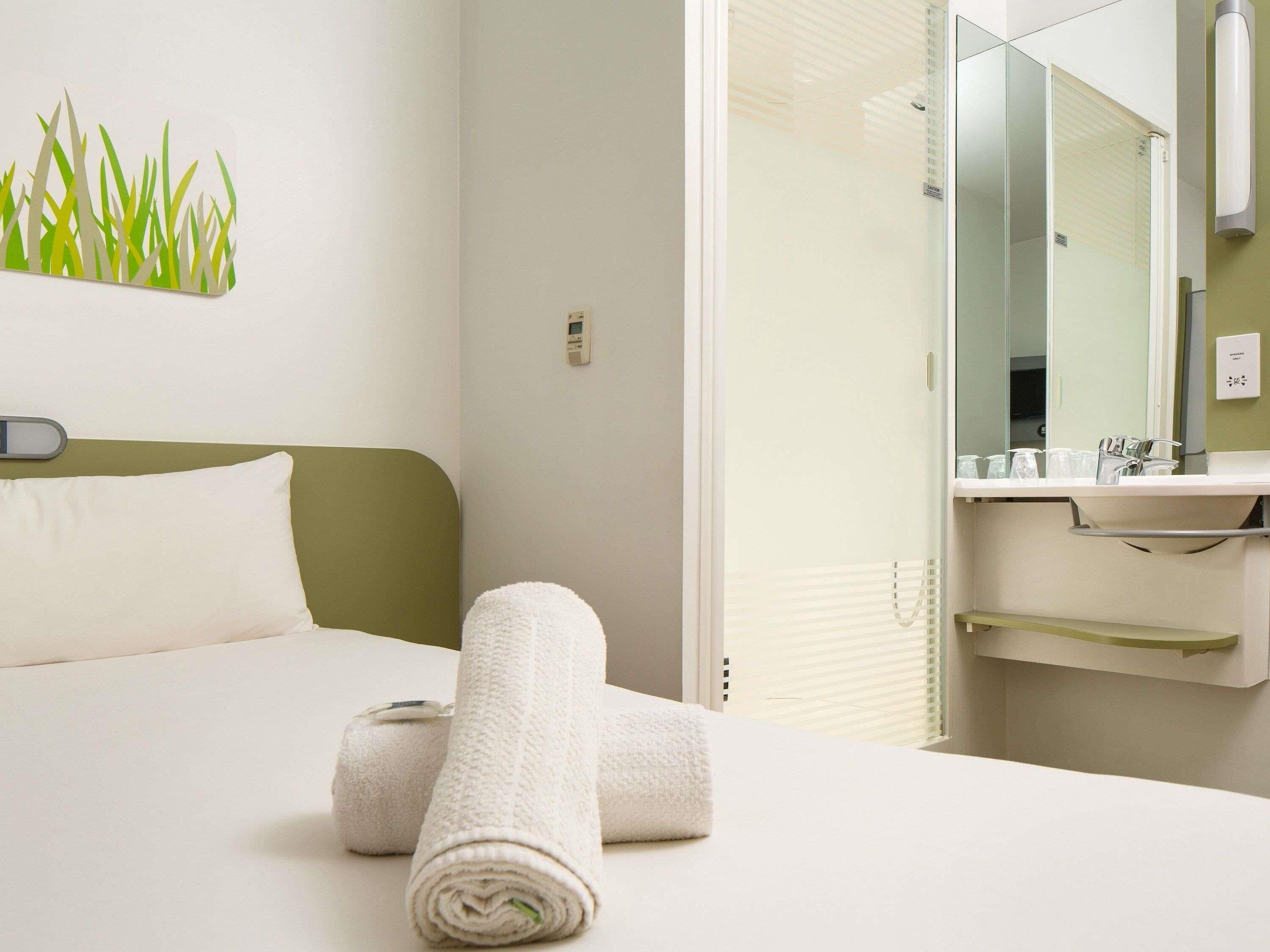 A hotel room with a bed, a bathroom with a mirror, and towels.