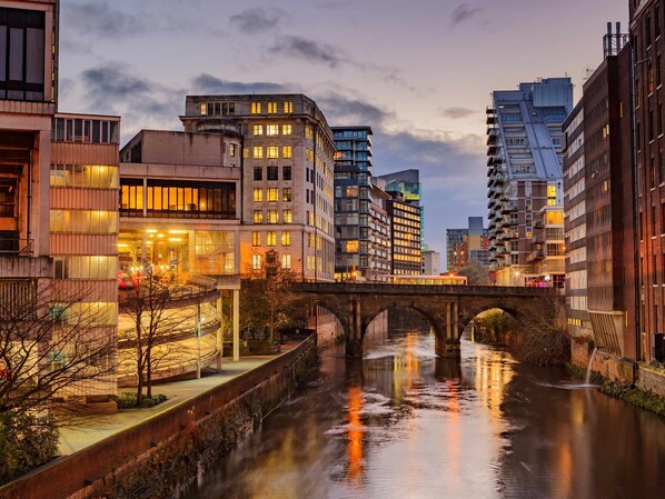Un río con un puente, edificios modernos y un entorno urbano bien iluminado.