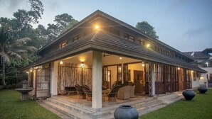 A two-story house with a covered porch, outdoor seating, and a well-maintained lawn. - Serenity Lake Front Villa (Moratuwa)