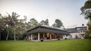 A house with a covered porch, surrounded by a well-maintained lawn and palm trees. - Serenity Lake Front Villa (Moratuwa)