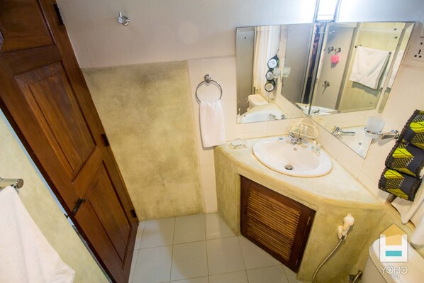A bathroom with a wooden door, a sink with a mirror, a towel rack, and a shower area. - Serenity Lake Front Villa (Moratuwa)