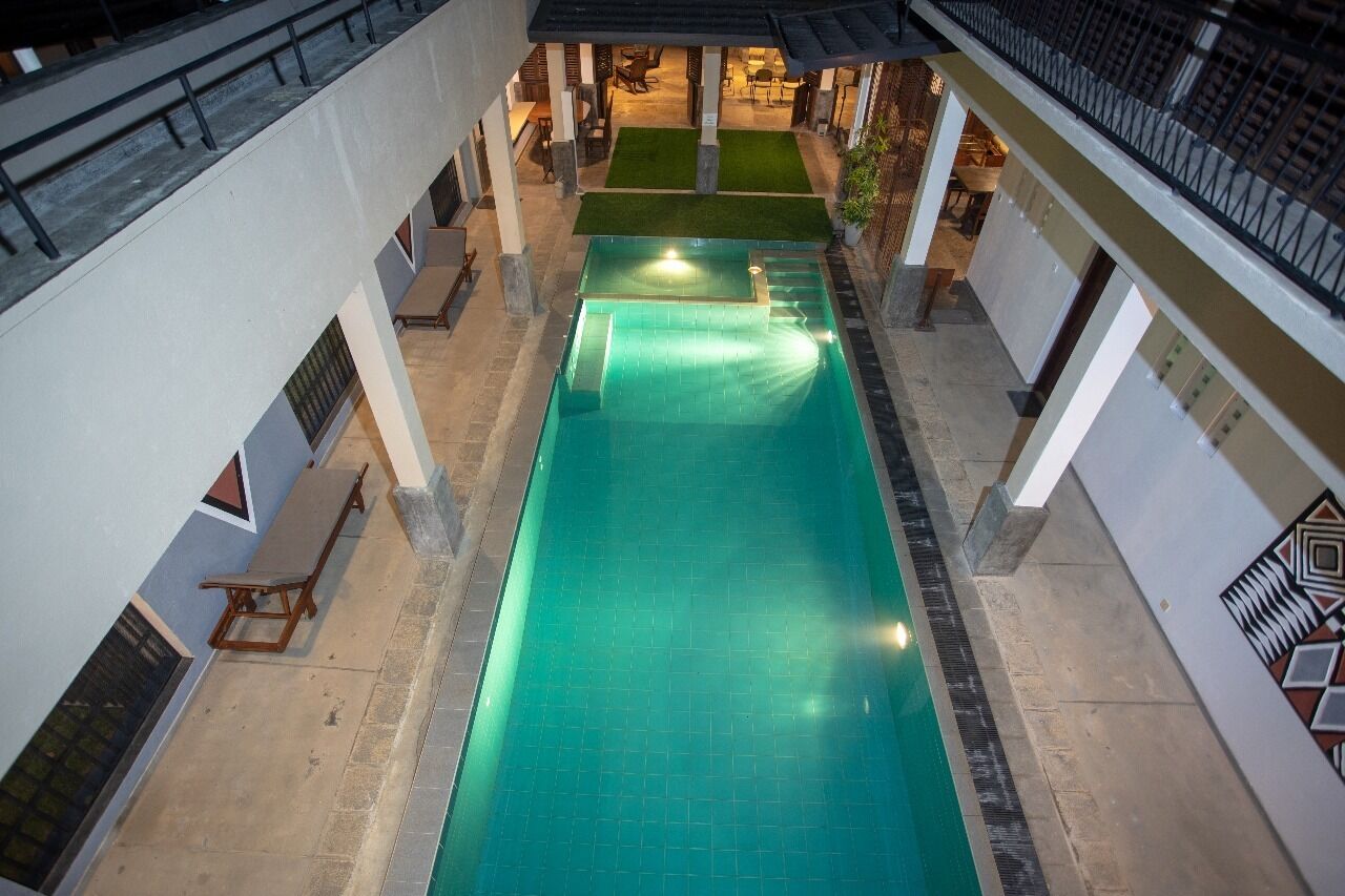 A rooftop swimming pool with a view of the surrounding area, including a seating area and a covered patio.