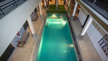 A rooftop swimming pool with a view of the surrounding area, including a seating area and a covered patio.