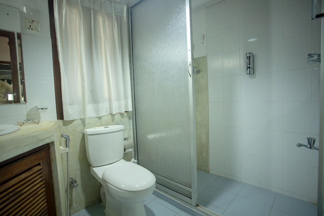 A bathroom with a toilet, a shower enclosure, and a sink.