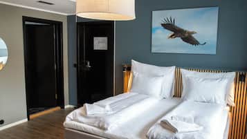 Habitación de hotel con una cama grande, una lámpara de techo, un cuadro de un águila y una puerta con un aviso.