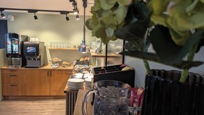 Una kitchenette con cafetera, zona de té y diversos alimentos sobre la encimera.