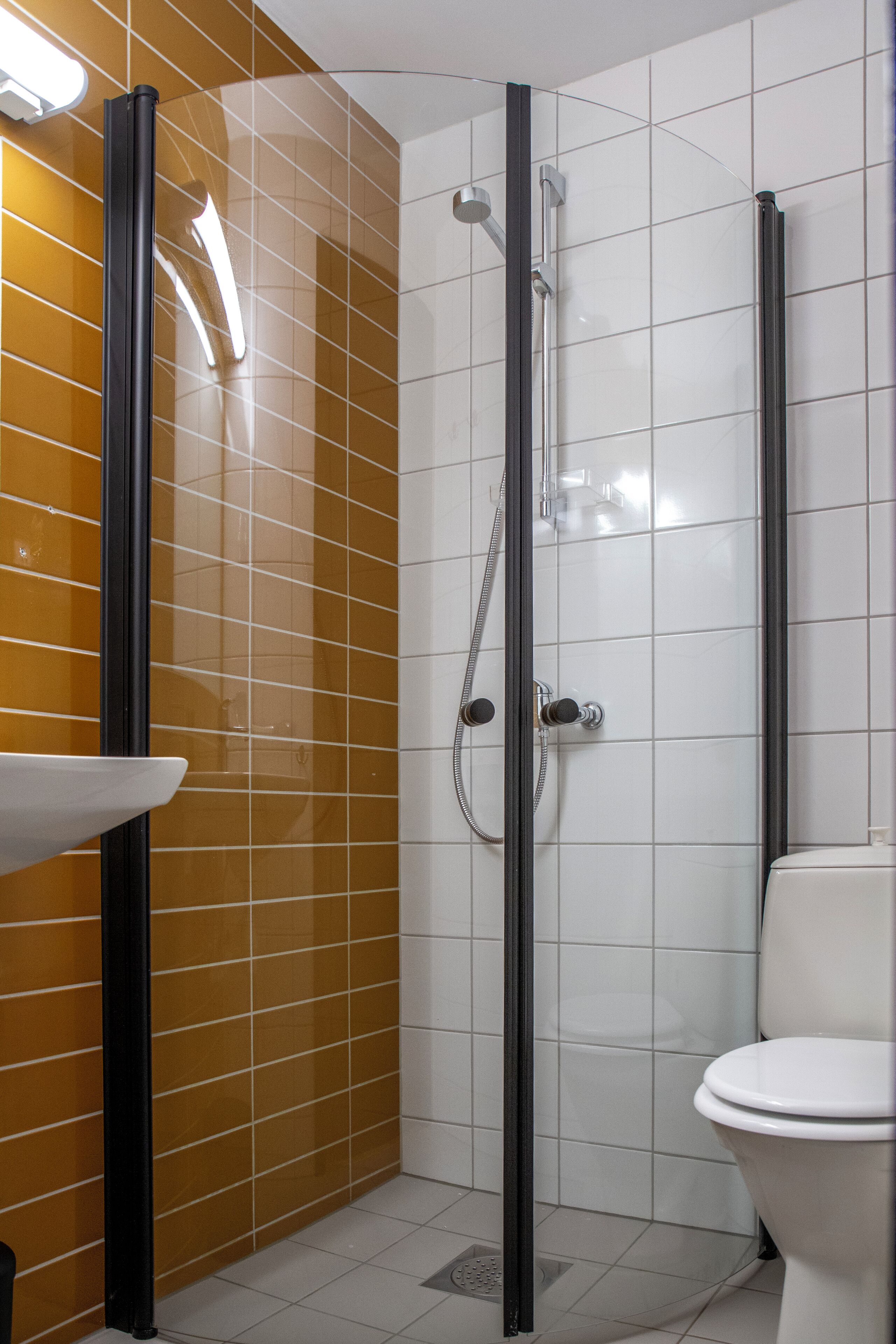 A bathroom with a glass-enclosed shower, a white toilet, and a sink with a black faucet.