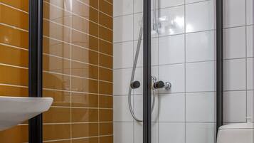 Ein Badezimmer mit einer Duschkabine, einer weißen Toilette und einem Waschbecken mit einem schwarzen Wasserhahn.