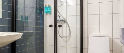 Een badkamer met een douchecabine van glas, een wit toilet en een wastafel.