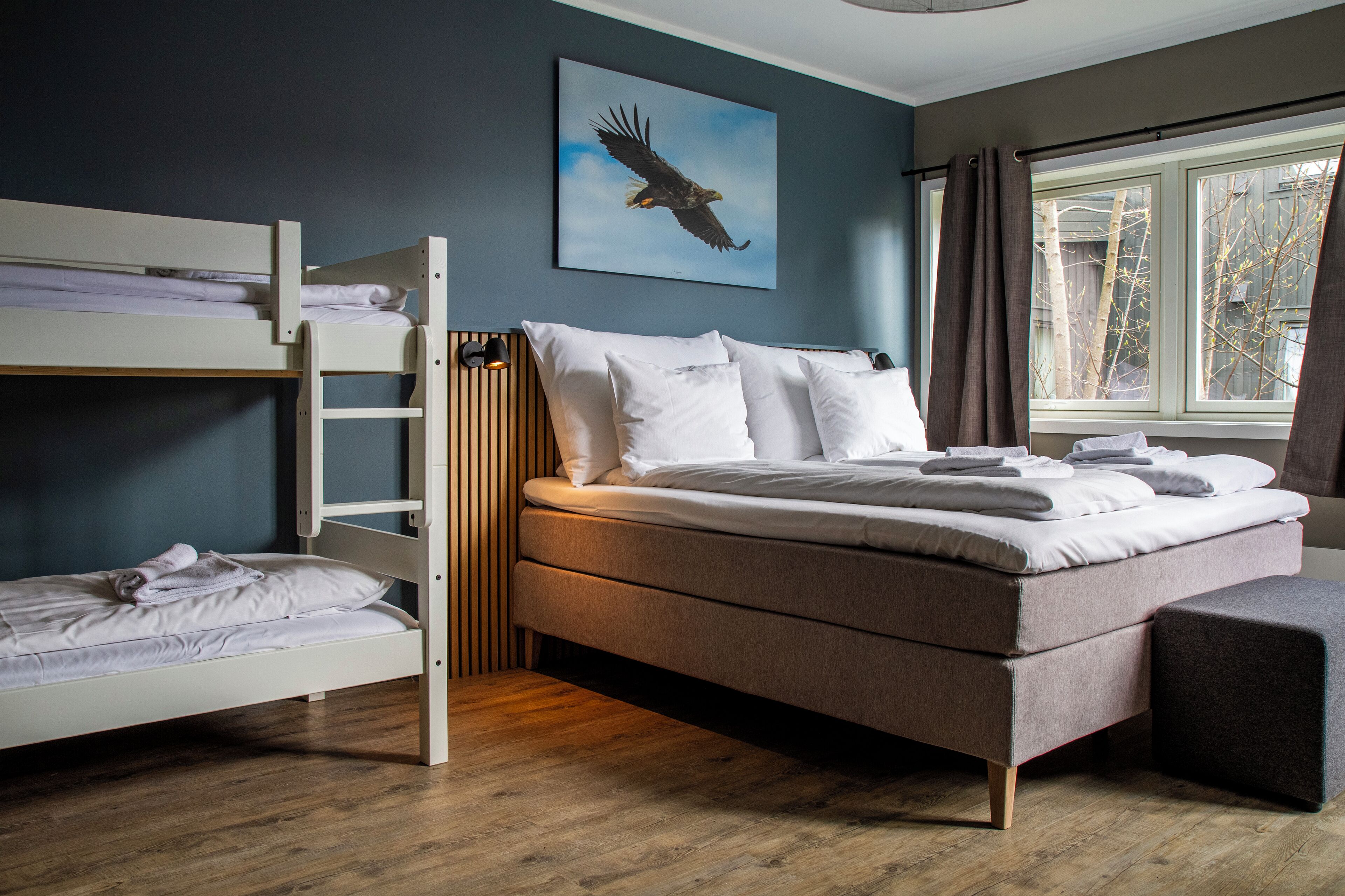 A bedroom with a bunk bed, a single bed, and a window with curtains.