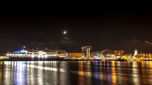 Un paisaje urbano frente al agua de noche, con edificios iluminados y un río que refleja luces.