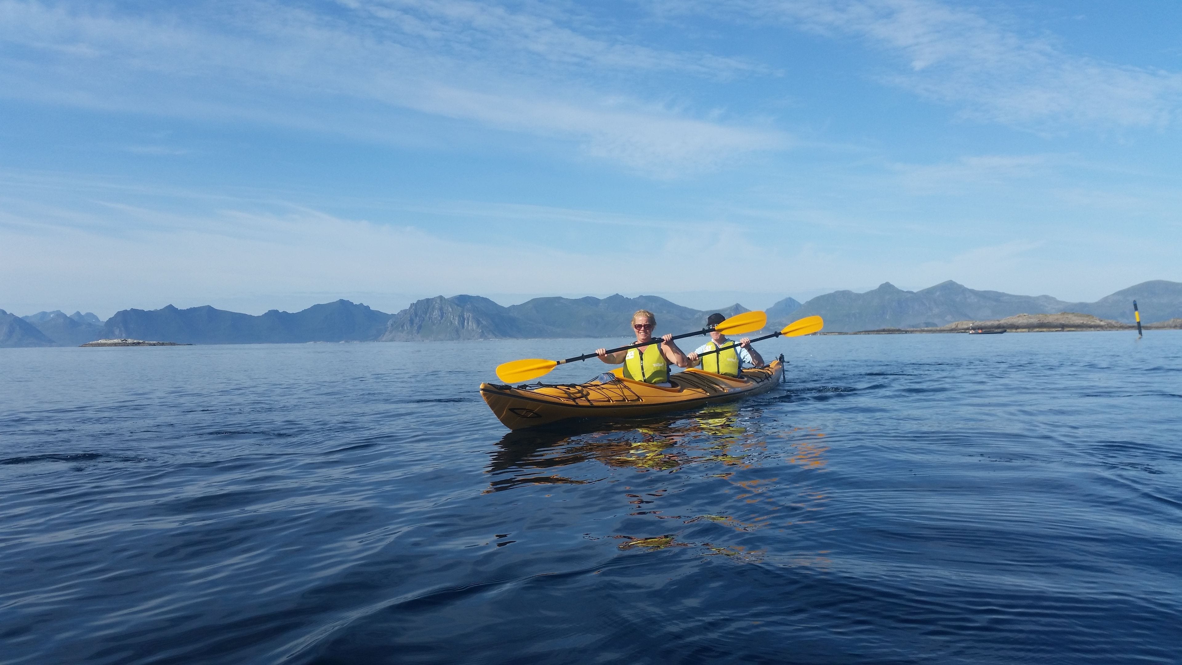 Een kajak op kalm water, met bergen op de achtergrond.