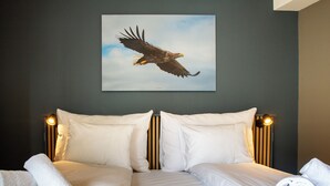 Una habitación de hotel con una cama grande, dos almohadas y dos toallas enrolladas.