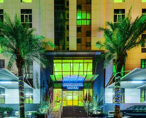The Bravo Royal Hotel entrance with a modern design, featuring a prominent sign and palm trees. - Bravo Royal Hotel Suite (Salmiya)