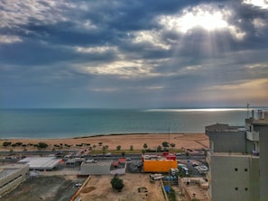 A coastal view with a beach, buildings, and a clear sky. - Bravo Royal Hotel Suite (Salmiya)