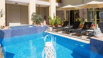 A pool area with lounge chairs and umbrellas, surrounded by balconies with yellow railings.