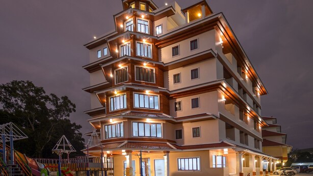 Un hotel de varios pisos con balcones, un parque infantil y un estacionamiento.