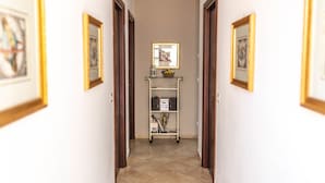 A hallway with framed artwork on the walls, a white console table with a mirror and decorative items, and a tiled floor. - Bed and Breakfast Dionisio (Taormina)