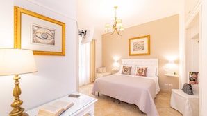 A hotel room with a bed, bedside tables, a desk with a lamp, and a chandelier. - Bed and Breakfast Dionisio (Taormina)