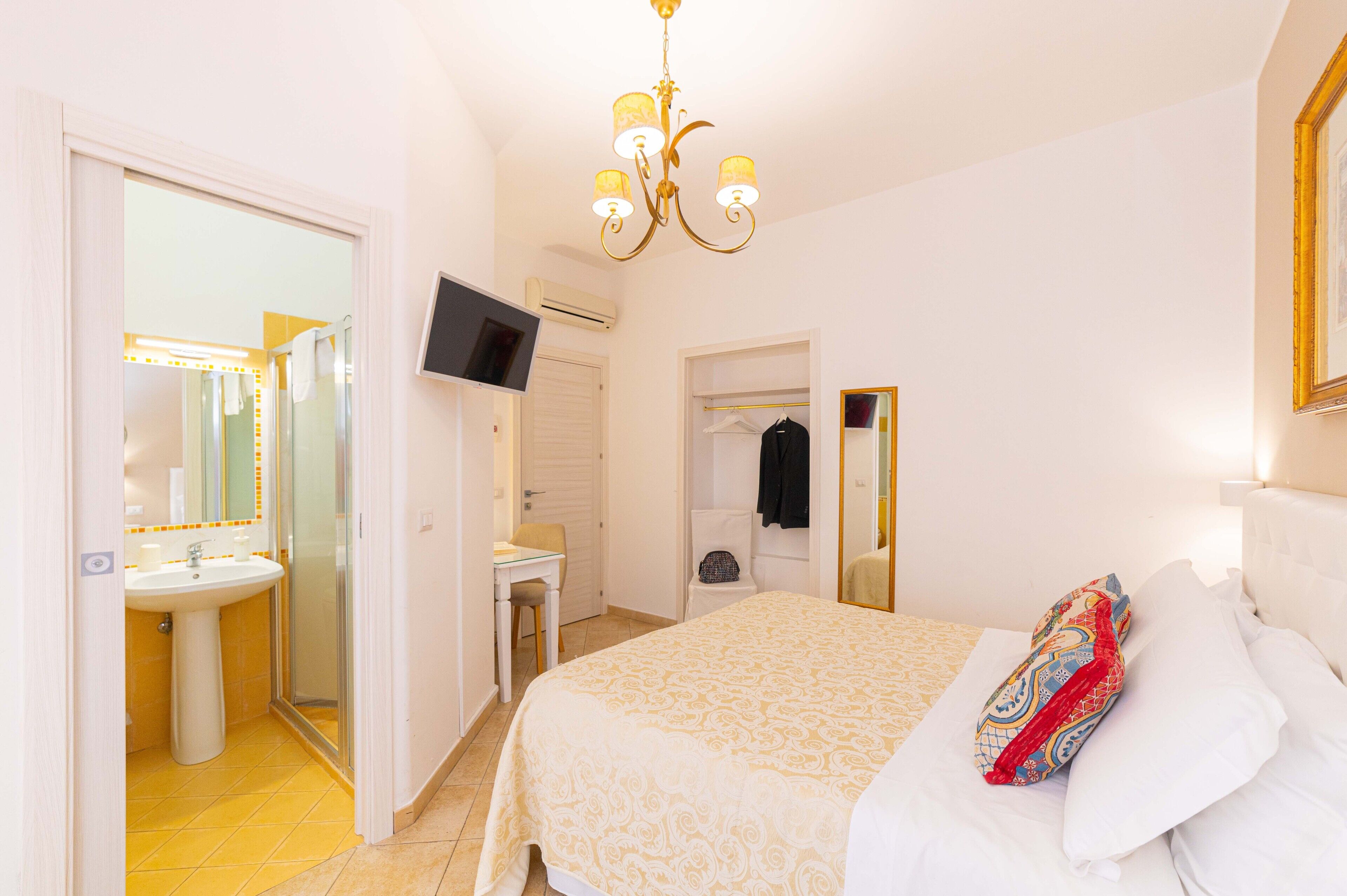 A bedroom with a bed, a bedside table, a mirror, and a wardrobe.