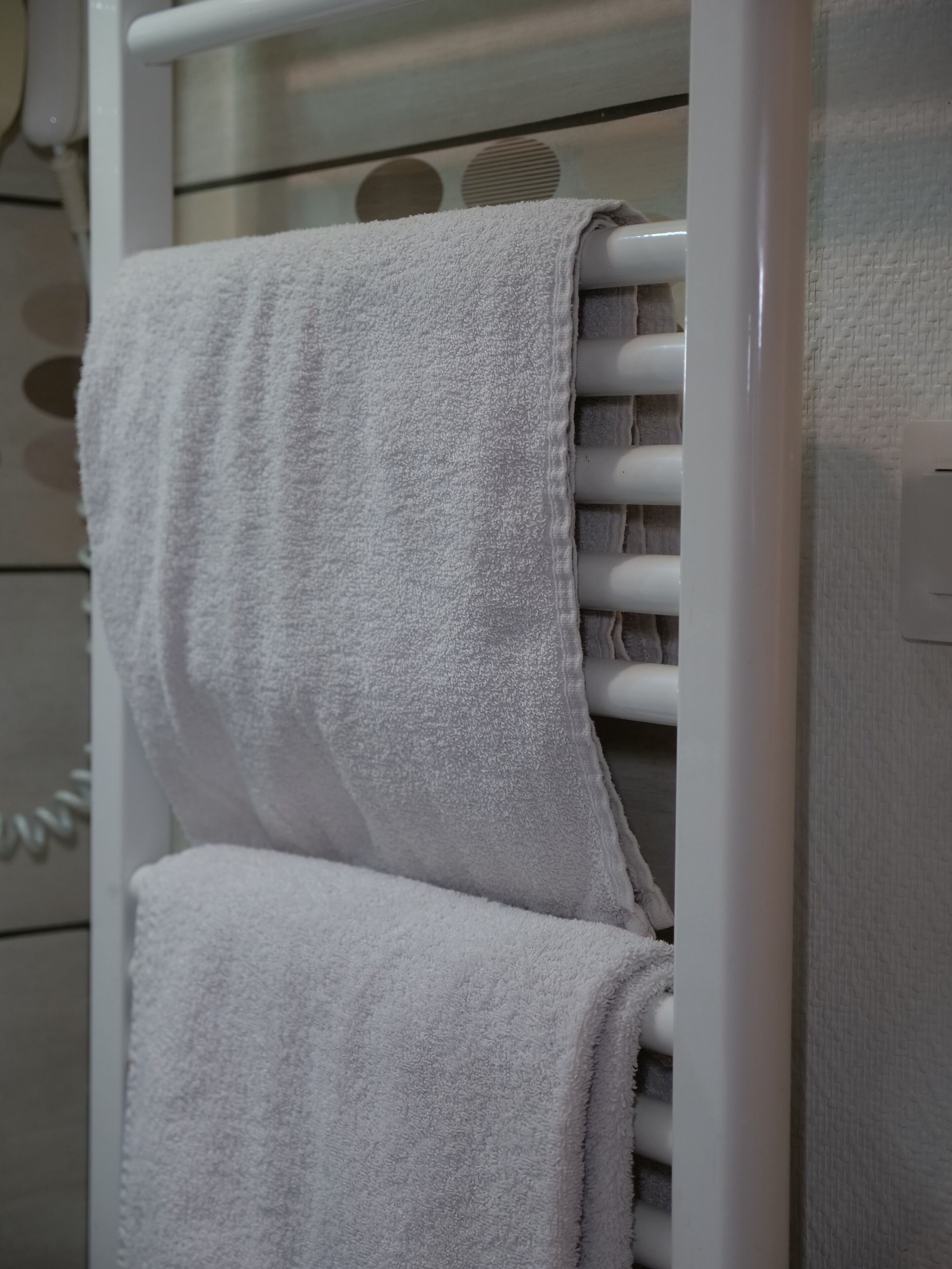 A white towel rack with two neatly folded towels.
