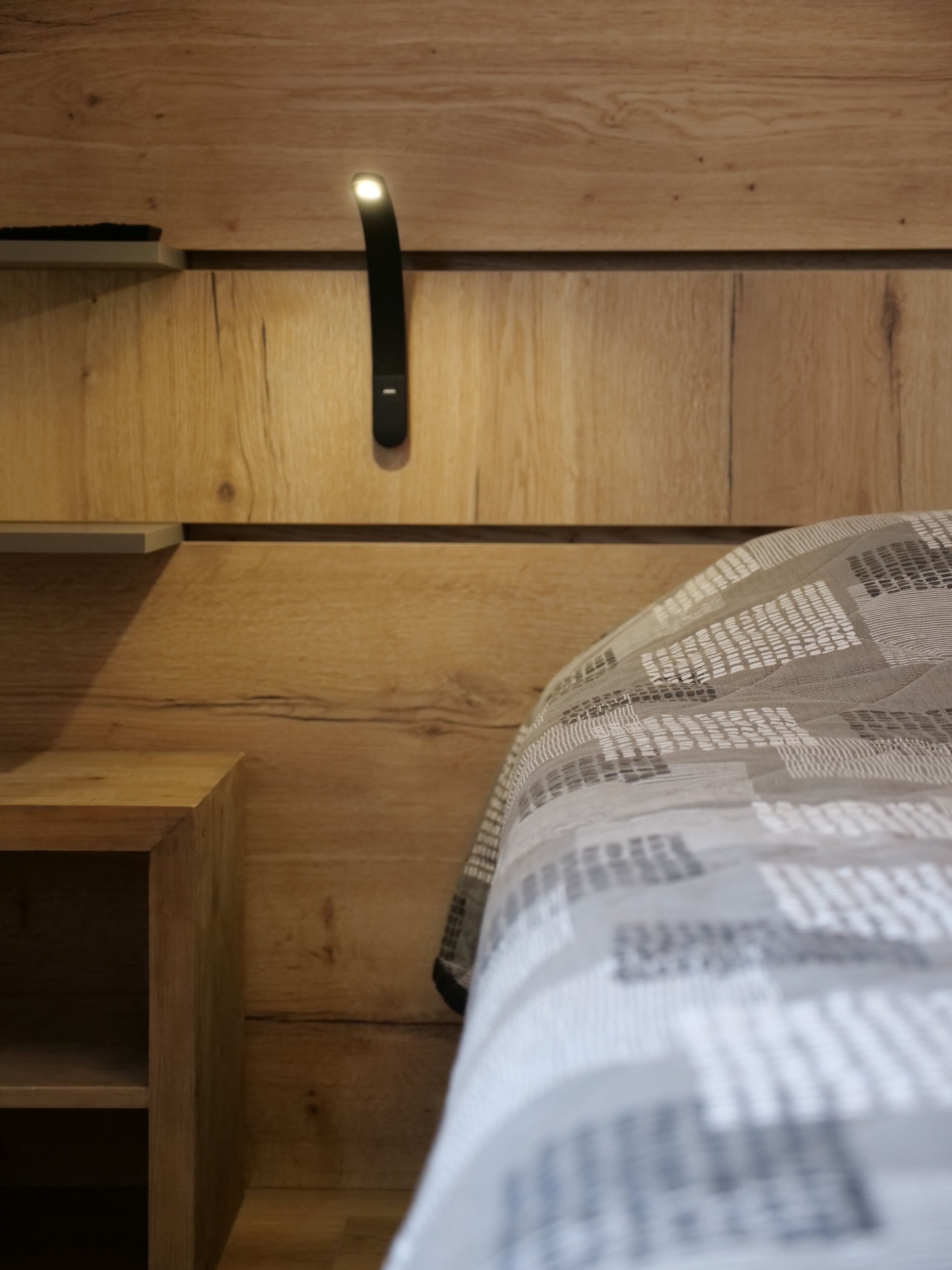Cabecera de madera con estante incorporado y lámpara de noche.