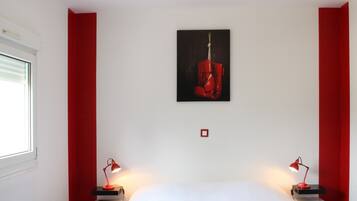 Un dormitorio moderno con una cama grande, dos mesitas de noche con lámparas, una ventana con persianas y un cuadro en la pared.